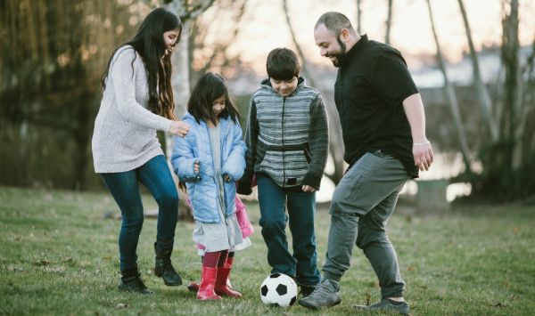 young family kicking a football to each other